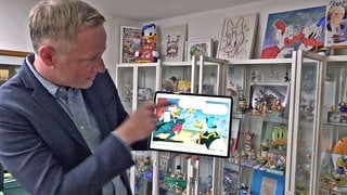 iPad-MagierSimon Pierro hat es in ein Mickey-Mouse-Comic geschafft. Er hält ein iPad in der Hand, auf dem er als Ente in einem Comic mit Donald Duck zu sehen ist.