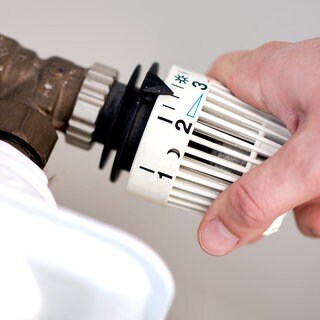 Eine Frau dreht am Thermostat einer Heizung: Die Stadt Koblenz hat ein Konzept für eine kommunale Wärmeplanung erarbeiten lassen. Sie will bis spätestens 2040 klimaneutral werden. 