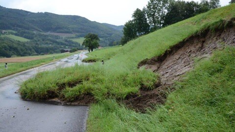 Kleiner Hangrutsch auf eine Straße nach Starkregen. Die Straße ist nicht mehr befahrbar. 
