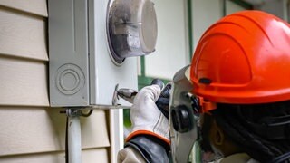 Handwerker schraubt an altem Stromzähler