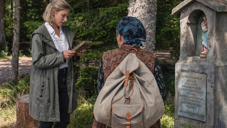 Lioba und Celine vor einem Gedenkstein am Waldrand