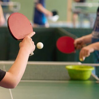 Ein Junge spielt Tischtennis mit einem Trainer.