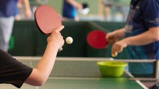 Ein Junge spielt Tischtennis mit einem Trainer.