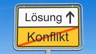 Illustration zum Thema Konflikt-Lösung: Ein Ortsschild zeigt das Wort "Lösung" und das durchgestrichene Wort "Konflikt".  Friedrich Glasl ist Konfliktforscher. Egal, ob Auseinandersetzungen in Beziehung oder Arbeitsplatz oder der Angriffskrieg von Russland auf die Ukraine: er analysiert sie und sucht Lösungen. Wir sprechen mit ihm in SWR1 Leute