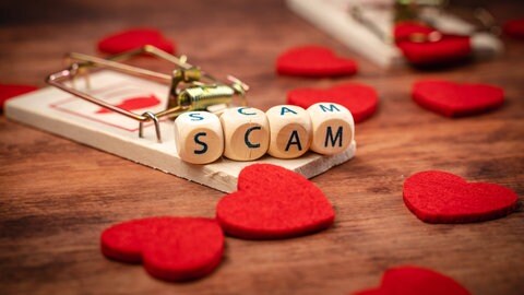 Eine Mausefalle, rote Herzen und Würfel mit Buchstaben, die das Wort "Scam" bilden (Symbolbild "Love Scamming").