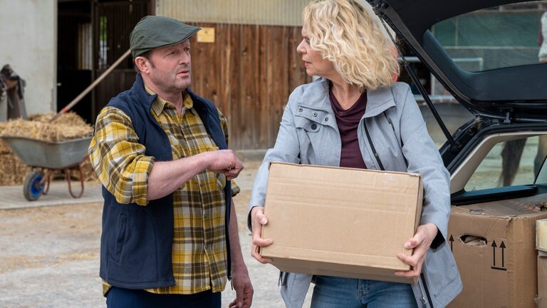Kati und Bernd beim Gestüt, Kati trägt einen großen Karton