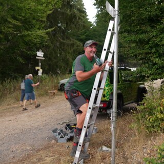Wegewart stellt Schild an einem Wanderweg im Schwarzwald auf