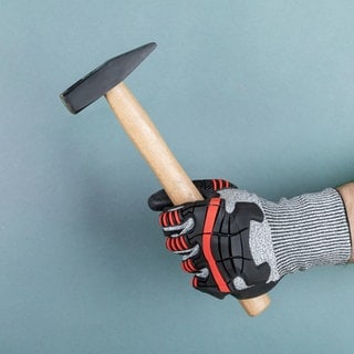 Hand mit Schutzhandschuh hält Hammer. Symbolfoto.