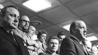 Bundesinnenminister Dietrich Genscher, Olympia-Pressechef Hans Klein, Münchens Polizeipräsident Manfred Schreiber und der bayerische Innenminister Merk (v.l.) auf einer Pressekonferenz in der Nacht zum 6.9.1972 im Pressezentrum der Olympischen Sommerspiele, auf der das ganze Ausmaß des Terror-Anschlags bekannt wird