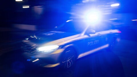 Ein Polizeifahrzeug fährt mit Blaulicht an einem Gebäude vorbei. . In Arnach bei Bad Wurzach im Kreis Ravensburg wollten Unbekannte einen ganzen Bankautomaten stehelen. 