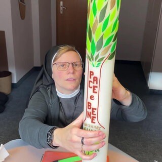 Schwester Tobia dekoriert eine Kerze