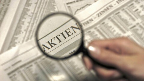 Lupe zeigt auf Börsenteil in Zeitung: Frauen investieren deutlich seltener in Aktien als Männer: 2021 gab es 4,3 Millionen Aktionärinnen und 7,8 Millionen Aktionäre