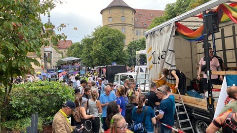Menschen stehen neben Wagen des CSD Stuttgart 2025 in der Nähe des Stuttgarter Schlossplatzes.