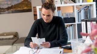 Eine Frau sitzt an ihrem Schreibtisch und macht die Steuererklärung | Wer nicht abgibt, verschenkt in der Regel ein paar hundert Euro: Warum ihr die Steuererklärung nicht aufschieben solltet