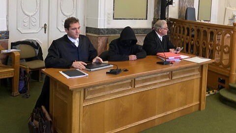 Prozess um Unfall mit Toten und Schwerverletzten durch mutmaßlichen Raser am Landgericht Landau, Angeklagter verhüllt Gesicht unter einer Kapuze 