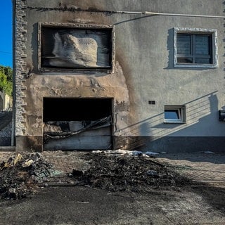 Der Tatort in Ober-Olm. Vor einem Wohnhaus sind die Spuren des Feuers zu sehen. Die mutmaßliche Täter stehen wegen Brandstiftung und Erpressung vor Gericht.