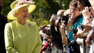 Königin Elisabeth die Zweite in einem gelben Kleid vor Publikum.