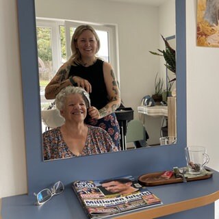 Julia Neumann frisiert ihre Kundin Irene Mertens, die in dem veganen Friseursalon in Waldlagesheim vor dem Spiegel sitzt.  