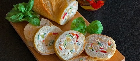 Gefülltes Baguette, sogenanntes Mosaikbrot, mit Essiggurken, Schinken und Käse.