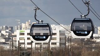 Zwei Gondeln der C1, der ersten städtischen Seilbahn in Paris, die 2025 in Betrieb ging. Jetzt planen Bonn und Herne Deutschlands erste ÖPNV-Seilbahn und kämpfen mit großen bürokratischen Hürden.