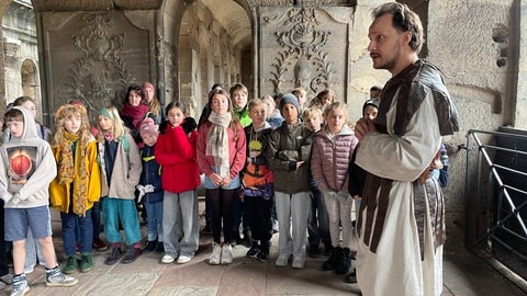 Ein Schauspieler lässt Kinder in der Porta Nigra Römische Geschichte erleben.