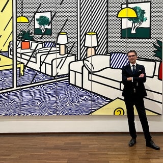 Ein Mann steht vor einem großen Pop-Up-Bild von Roy Lichtenstein