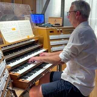 Ein Mann sitzt an der Orgel im Ulmer Münster.