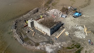 Bauarbeiter sanieren eine alte Mauer um die Insel Hoy. Hoy ist mit 53 Quadratmetern die kleinste Insel im Bodensee und normalerweise vom Wasser umspült. Wegen des aktuell sehr niedrigen Wasserstands können Baumaschinen trocken bis dorthin fahren. 