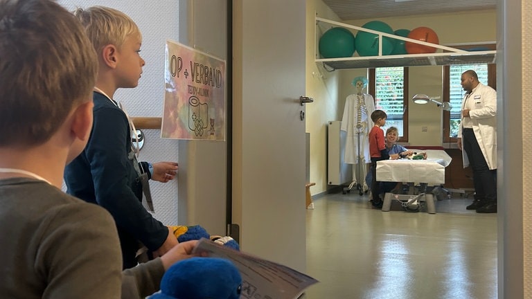 Kinder blicken auf OP-Zimmer und warten darauf, hereingerufen zu werden.