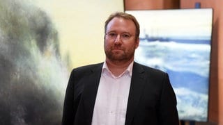 Elger Esser in einer seiner Ausstellungen, Fotos im Hintergrund.