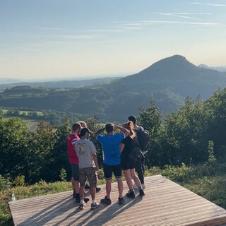 Die Wandergruppe Wandersocken steht auf einer Aussichtsplattform und schaut in die Ferne. Beim gemeinsamen Wandern werden aus Fremden oft Freunde.