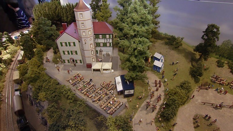 Über der vielbefahrenen Eisenbahnstrecke thront eine Ritterburg. Ein rauschendes Fest findet gerade statt, von den Modellbahnfreunden Rödental ausgestattet mit zahlreichen Figuren.