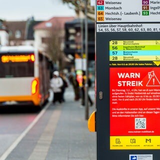 Ein Display in Mainz informiert über den Warnstreik im ÖPNV, während Menschen in einen der wenigen Busse einsteigen, die noch verkehren. 