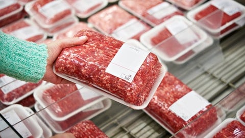 Man sieht eine Hand, die abgepacktes Fleisch hält. Können unterbrochene Kühlketten und zu warme Kühlschränke die Haltbarkeit von Fleisch und Fisch gefährden? Laboranalysen zeigen, ab wann die Qualität der Frischeprodukte beeinflusst wird. 