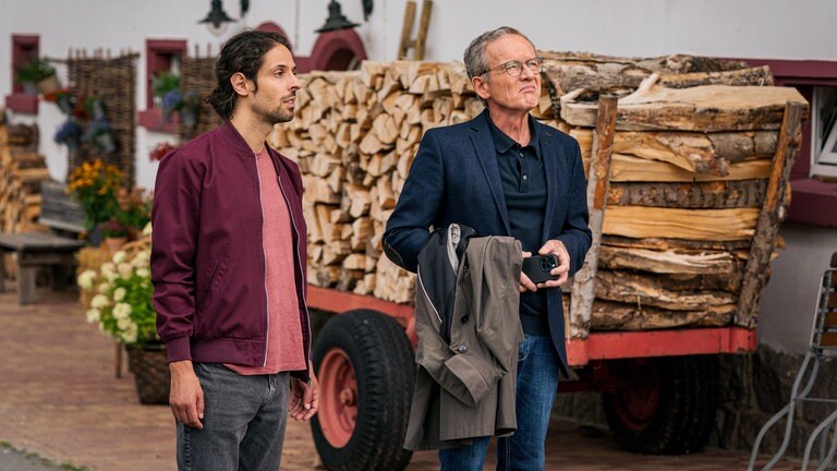 Albert (Alessio Hirschkorn) und Bernhard (Karsten Dörr) stehen hinterm Hofladen vor einem mit Holz beladenen Wagen