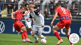 Eine Szene aus dem DFB-Pokalspiel: Jeddelohs Pascal Steinwender von Jeedeloh kämpft gegen Heidenheims Jan Schöppner und Patrick Mainka um den Ball. Recht unten das SWR-Logo für Leichte Sprache.