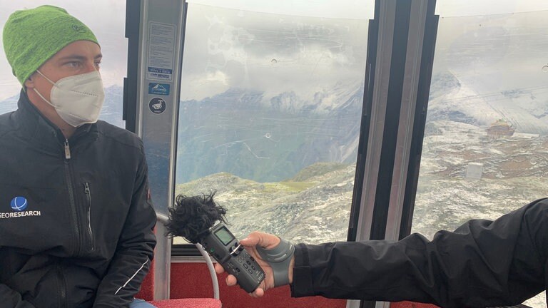 Ingo Hartmeyer von Geo Research: Am Kitzsteinhorn in rund 3.000 m Höhe schneit es sogar im August. Ingo Hartmeyer von Geo Research muss heute Messungen am Berg durchführen. Wir dürfen ihn in einer der Gondeln begleiten. Seit 2010 führen Hartmeyer und sein Team hier regelmäßig Messungen durch – u.a. werden die Felswände mit Laserscannern abgetastet. Wichtigste Erkenntnis: Wo die Gletscher schwinden, gibt es deutlich mehr Steinschlag.