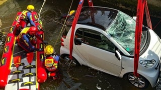 Retter der DLRG und ein Kleinwagen in einem Kanal in Langenargen. Das Auto war ins Wasser gestürzt und wurde geborgen.