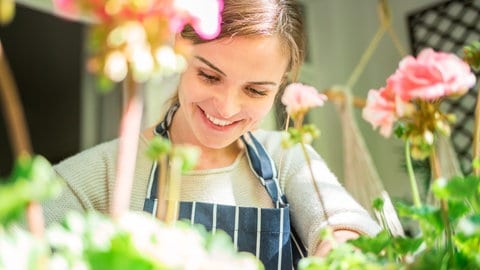 Eine Frau pflegt die Geranien auf ihrem Balkon