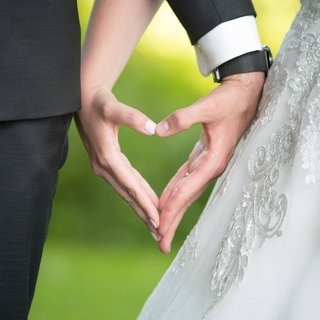 Ein Hochzeitspaar bildet mit seinen Händen ein Herz.