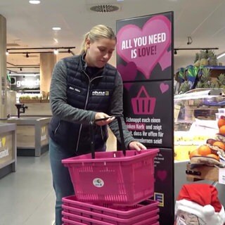 Eine Frau nimmt einen pinken Einkaufskorb