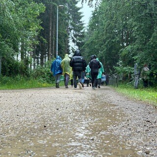Rock am Ring-Fans laufen auf matschigem Weg durch den Regen