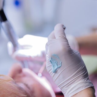 Eine Zahnarzthelferin führt an einer Patientin eine Zahnreinigung durch.