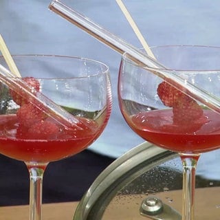 Sommercocktail mit weißem Tee, Himbeeren und Rosenknospen