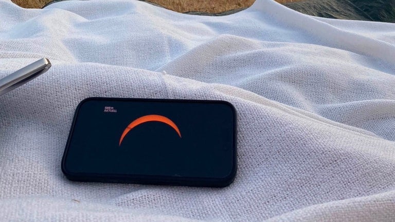 Eine Picknick-Decke liegt auf dem Boden. Darauf ein Tablet, worauf der SWR Aktuell Livestream läuft.