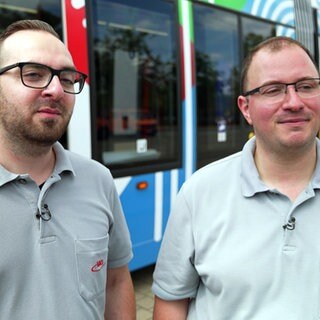 Marco und Daniel Rungenhagen stehen in Freiburg vor einer Straßenbahn