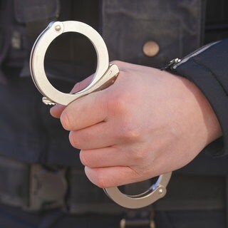 Ein Polizist hält Handschellen in der Hand. 
