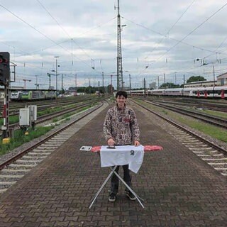 Mann mit Bügelbrett am Bahnhof