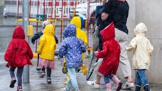 Eine Kindergartengruppe rennt während eines einsetzenden Gewitterregens über den Bürgersteig. (Symbolbild)