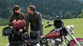 Eva und Andreas mit dem Motorrad vor einer großen Wiese